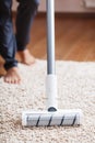 Human legs and a white turbo brush of a cordless vacuum cleaner cleans the carpet in the house Royalty Free Stock Photo