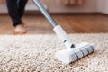 Human legs and a white turbo brush of a cordless vacuum cleaner cleans the carpet in the house Royalty Free Stock Photo