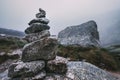 Human-made pile of stones - cairn as way marker in foggy mountai