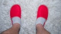 Human,male legs in slippers standing on a white rug,top view,red slippers,home lifestyle.