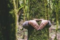 Human man hands embracing green tree trunk in the forest doing earth sign symbol for environment and nature love concept lifestyle Royalty Free Stock Photo