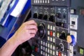 Operator hand spinning jog handle on CNC machine control panel. Close-up with selective focus and blur. Royalty Free Stock Photo