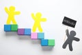 Human paper figures and stairs made of cubes on background, flat lay. Concept of jealousy