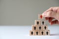 Hand putting wood cube block on top pyramid for leadership concept Royalty Free Stock Photo