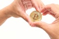 Human`s hand shaping heart symbol against cryptocurrency golden bitcoin on white isolated background. Virtual digital money conce