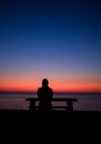 Human silhouette relaxed sitting at table at sea in the sunset time Royalty Free Stock Photo