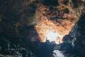 Human silhouette stands inside the cave with light coming from the ceiling