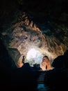 Human silhouette stands inside the cave with light coming from the ceiling