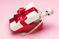 Human skeleton in a gift box on a pink background. Untimely gift concept Royalty Free Stock Photo