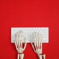 Human skeleton using computer keyboard on red background. Space for text Royalty Free Stock Photo