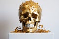 a human skull covered in gold leaf, placed on a white pedestal