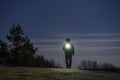 Human standing outdoor at night with flashlight and hoodie on head