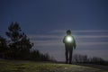 Human standing outdoor at night with flashlight and hoodie on head