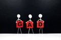 Human stick figure holding red GAD or Generalized Anxiety Disorder acronym banner. Black background.