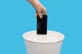 Human throws a broken mobile phone into a trash can on a blue background Royalty Free Stock Photo