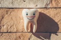 Human tooth against beige stone background with shadow, dental