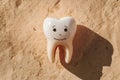 Human tooth against beige stone background with shadow, dental