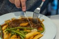 Human using knife and fork cutting juicy grilled beefsteak