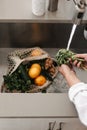 Human is washing local fruits and vegetables. From the farmers market. Zero waste. Net cotton organic shopping bag. Metal sink,