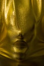 Human face pressing through golden fabric