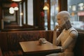 A humanoid robot sitting in a bar or cafe in the evening waiting and thinking Royalty Free Stock Photo
