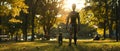 A humanoid robot takes a leisurely walk with a black dog through a park bathed in the golden light of an autumn sunset. Royalty Free Stock Photo