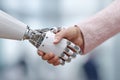 A humanoid robotic hand engages in a handshake with a human hand during a technology demonstration at a science exhibition. The Royalty Free Stock Photo