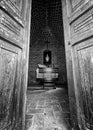 Humble chapel altar seen through ajar doors in black and white photo Royalty Free Stock Photo