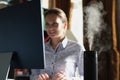 Humidifier with rising steam on desk of office employee Royalty Free Stock Photo