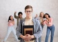 Humiliation and bullying at school. Focus on sad young guy in glasses and notebooks
