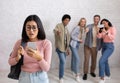 Humiliation, education and bullying. Sad asian young female in glasses looks at phone