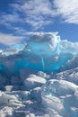 Hummocks of turquoise blue ice blocks under white clouds, vertical Royalty Free Stock Photo