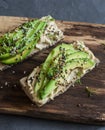 Hummus and avocado baguette sandwich with sesame and flax seeds on a wooden cutting board, on a gray background. Healthy eating Royalty Free Stock Photo