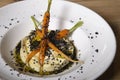 Hummus with black olive powder, olive oil and carrots served on a white porcelain plate. Isolated image