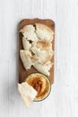 Hummus in bowl with roasted chickpeas, paprika, olive oil and pita bread on rustic wooden board over white wooden background, over Royalty Free Stock Photo