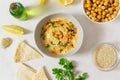 Hummus in a ceramic white bowl with paprika and parsley leaves and ingredients on a light background. Royalty Free Stock Photo