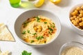 Hummus in a ceramic white bowl with paprika and parsley leaves and ingredients on a light background. A traditional Middle Eastern Royalty Free Stock Photo