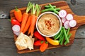 Hummus dip with a platter of vegetables, over wood Royalty Free Stock Photo