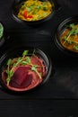 Hummus garnished peppers, chili, beet and herbs in black bowl on dark wooden table. Hummus assortment Royalty Free Stock Photo