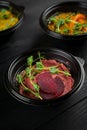 Hummus garnished peppers, chili, beet and herbs in black bowl on dark wooden table. Hummus assortment Royalty Free Stock Photo