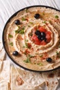 Hummus with olives and herbs on a plate close-up. Vertical Royalty Free Stock Photo