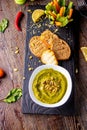 Hummus with spinach, avocado and pumpkin seeds in a bowl on a wooden board and bruschetta, oriental and Arabic cuisine , vertical Royalty Free Stock Photo