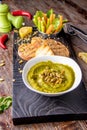 Hummus with spinach, avocado and pumpkin seeds in a bowl on a wooden board and bruschetta, oriental and Arabic cuisine , vertical Royalty Free Stock Photo