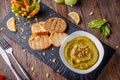 Hummus with spinach, avocado and pumpkin seeds in a bowl on a wooden board and bruschetta, oriental cuisine, horizontal Royalty Free Stock Photo