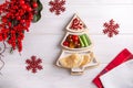 Hummus with vegetables and pita served on Christmas tree plate on white wooden background. Festive holiday snack. Top view