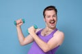 Humorous athletic man using small dumbbells for bodybuilding