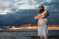 Humorous portrait of a brutal man posing on the beach at sunset Royalty Free Stock Photo