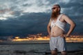 Humorous portrait of a brutal man posing on the beach at sunset Royalty Free Stock Photo