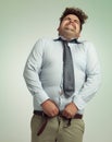 Willing his pants closed. Humorous studio shot of an overweight businessman trying to button his pants.