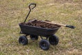 humus in a four-wheeled garden cart. Cloudy spring day